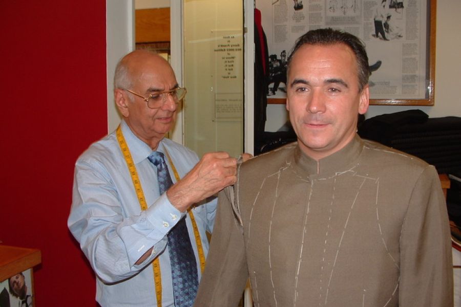 Lal Bhambi hand-cutting a bespoke suit pattern at Bhambi's Custom Tailors NYC – precise measurements for made-to-measure menswear